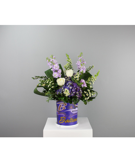 A festive purple and white Baltimore Ravens arrangement designed in a reusable tin container.